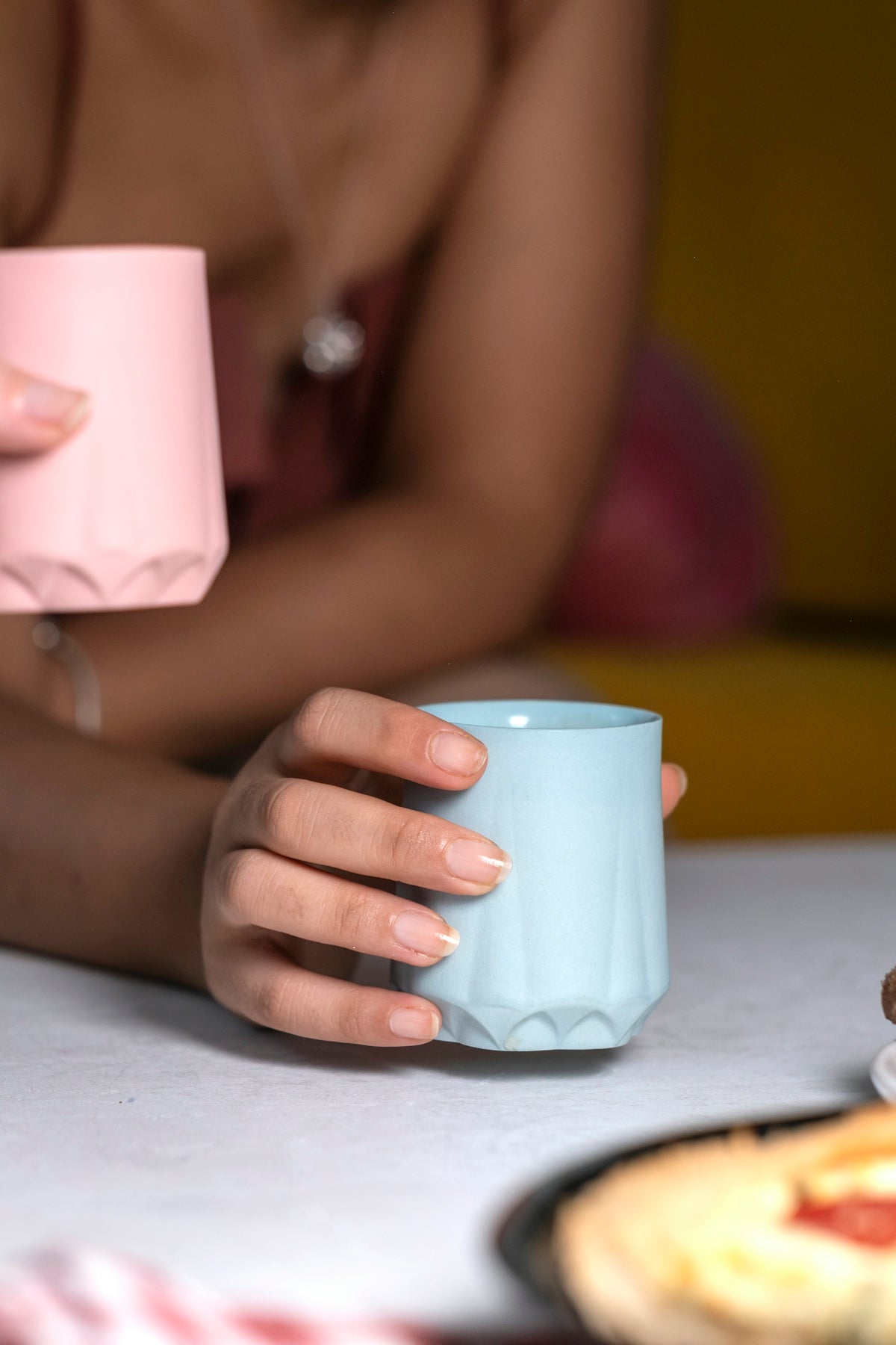 A woman sitting at a table holding a cup