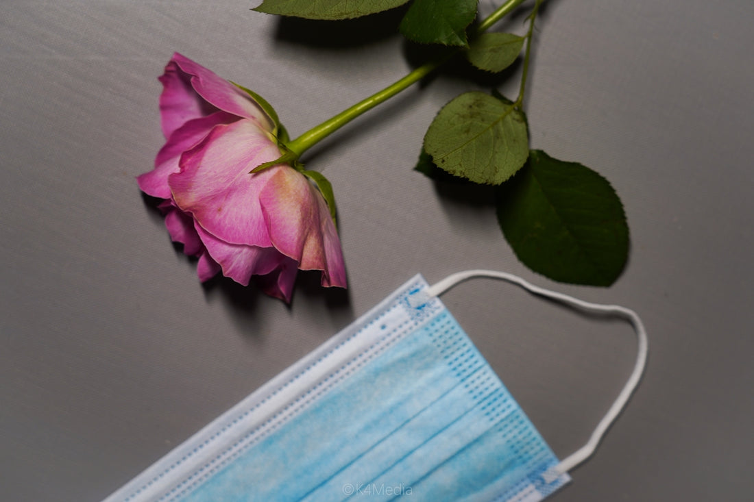 a pink rose with a medical mask next to it