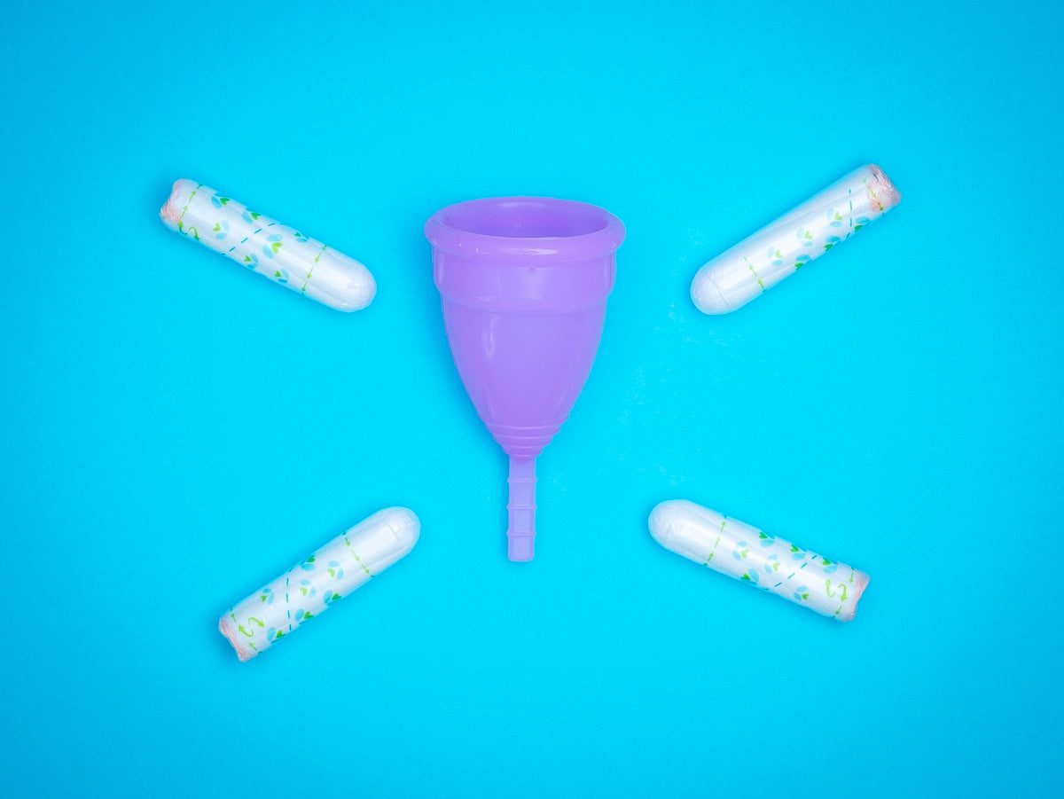 a purple plastic cup surrounded by five white pills