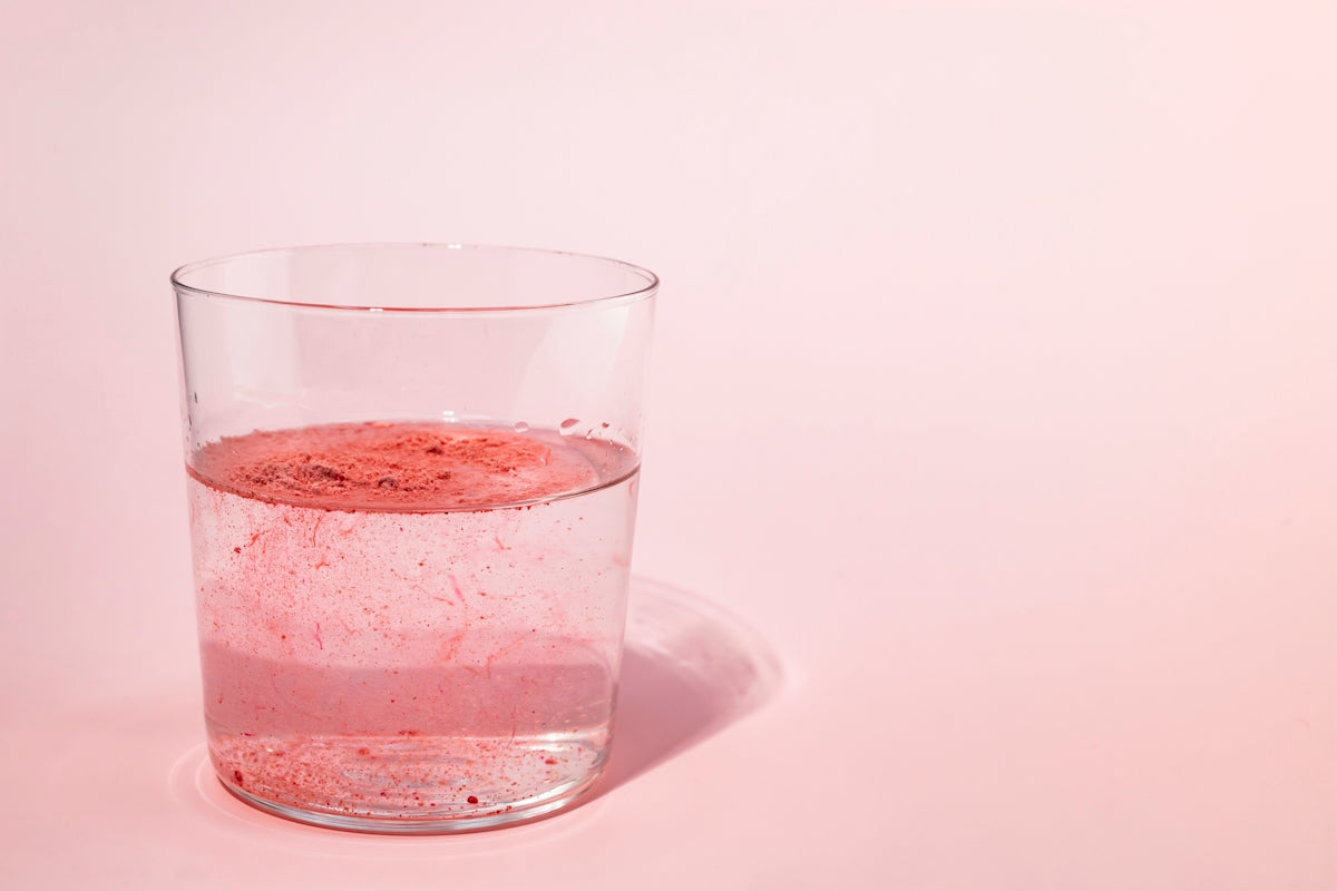 A glass of pink liquid on a pink background