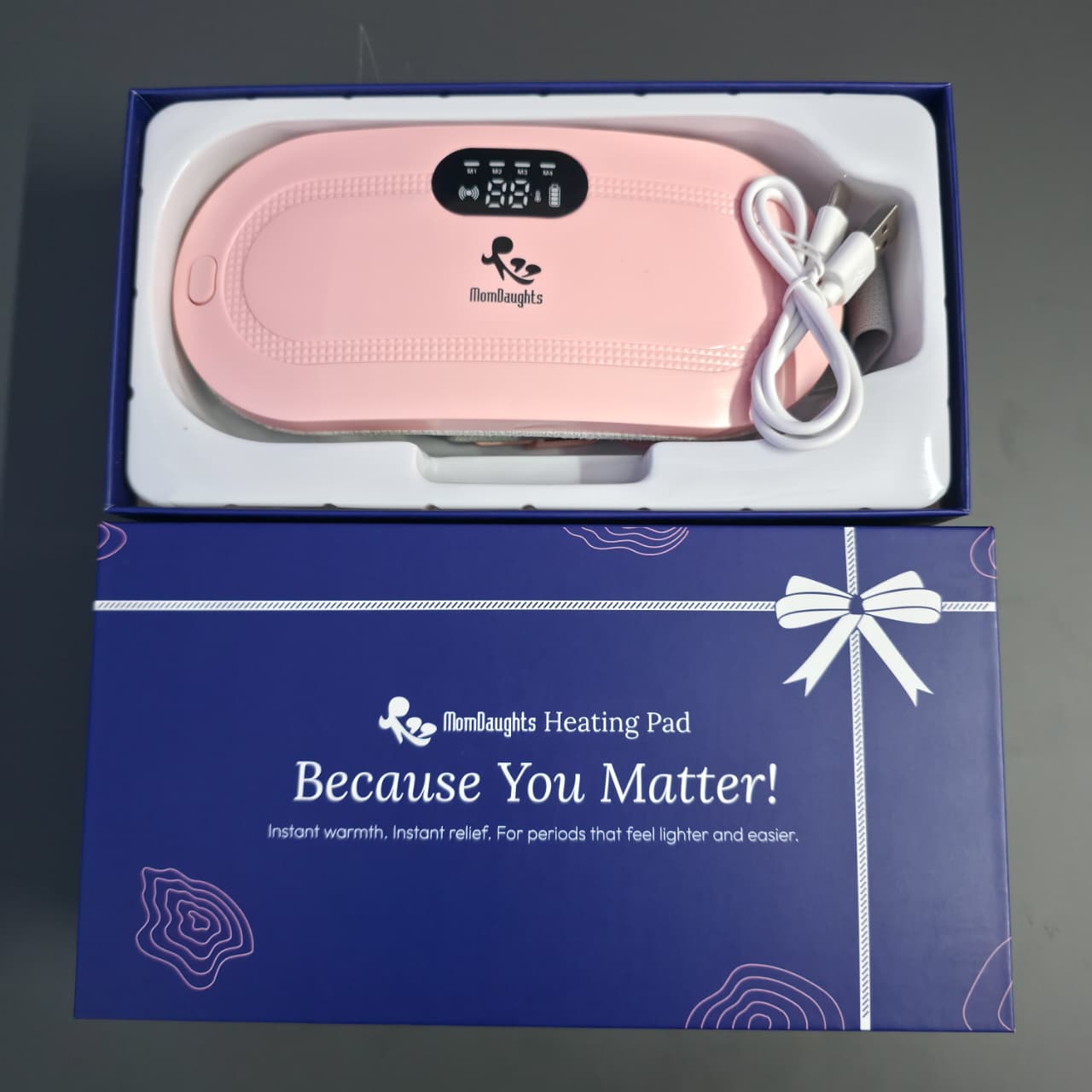 Pink heating pad with digital display in a blue box labeled 'Because You Matter'.